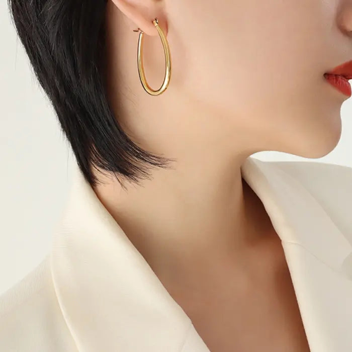 Classic gold hoop earring shown worn against neutral background