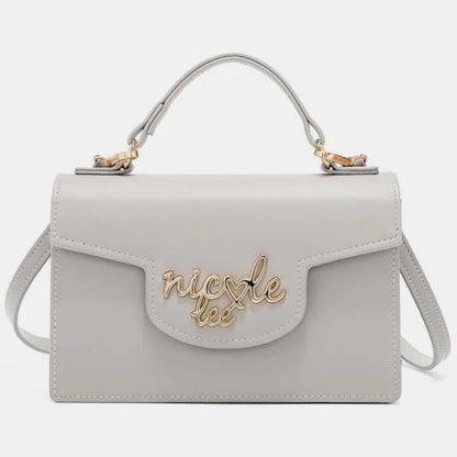 Gray leather handbag with gold logo, top handle, and flap closure, featuring a structured rectangular shape