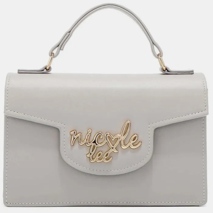 Grey leather handbag with gold hardware and cursive logo on front flap