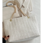 Elegant cream textured tote bag with gold chain strap on light background
