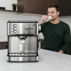 Espresso machine stainless steel on kitchen counter with man drinking espresso in the background.