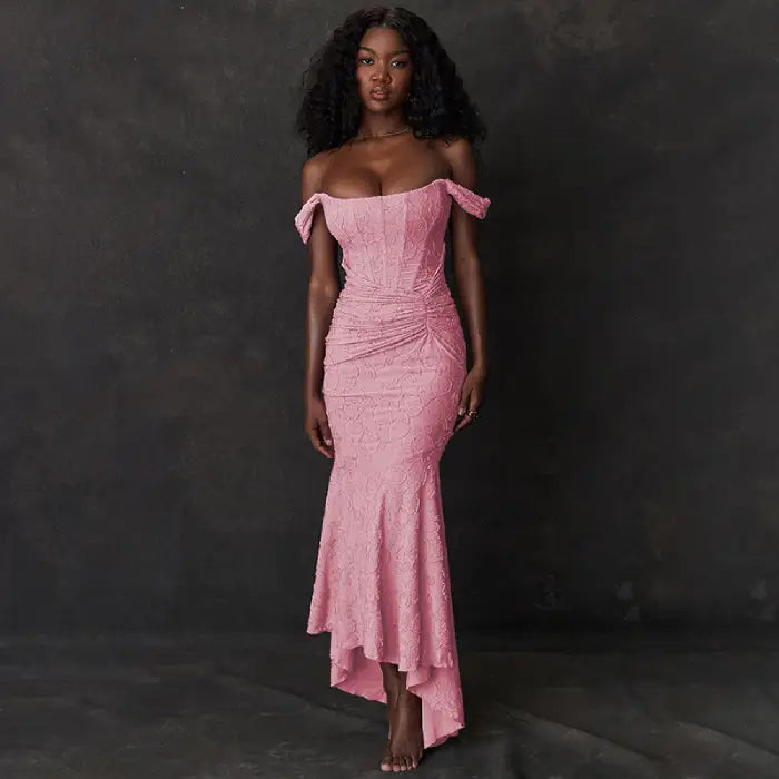 Evening dress in soft rose featuring asymmetric off-shoulder design, gathered waist detail and elegant trumpet silhouette with high-low hem