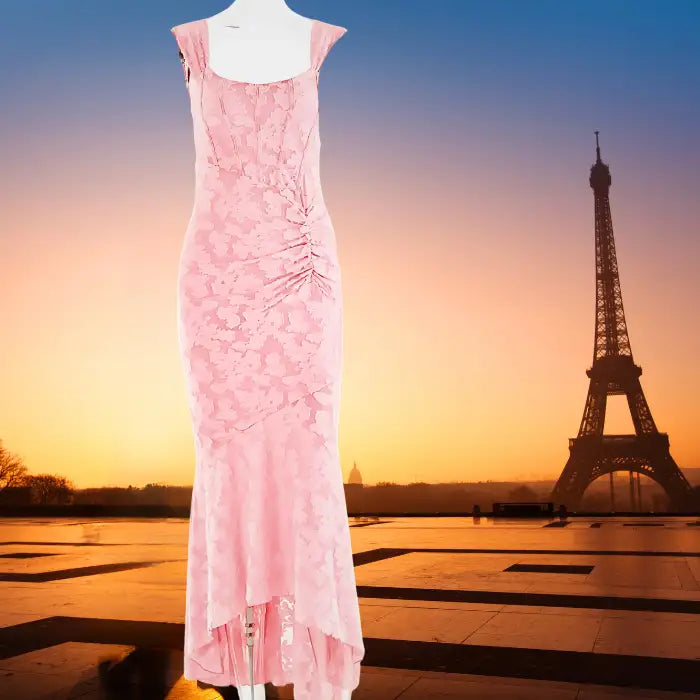 Evening dress in pink textured fabric displayed against iconic Paris sunset backdrop with Eiffel Tower silhouette