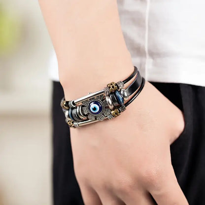 Fashionable evil eye bracelet with leather straps worn on a wrist, showcasing detailed metallic design.