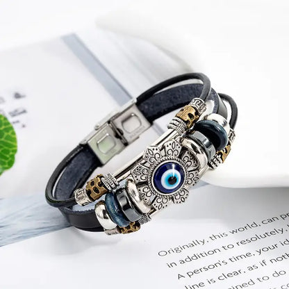 Elegant evil eye bracelet with layered leather straps and metallic accents on a white background.