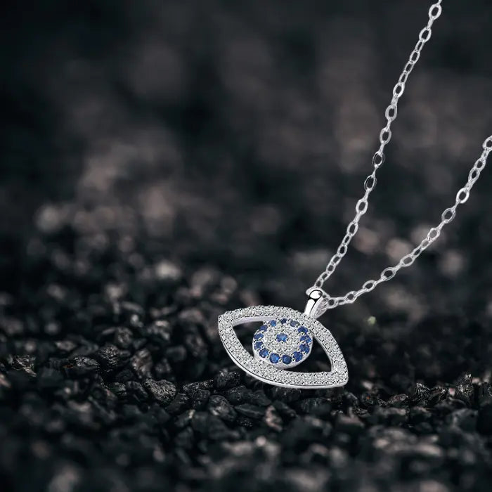 Evil eye protection necklace angled view on dark background highlighting fine chain and sparkling pendant.