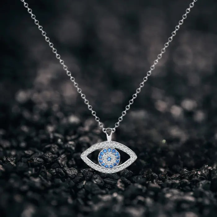 Evil eye protection necklace on textured black surface showcasing silver pendant with blue center stones.