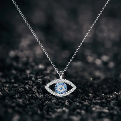 Evil eye protection necklace on textured black surface showcasing silver pendant with blue center stones.