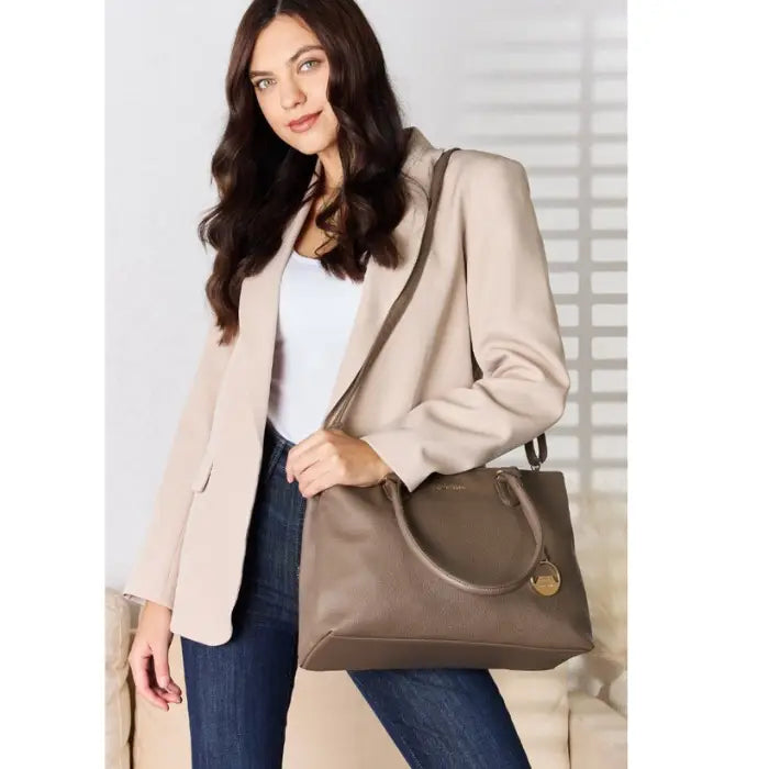  Fashionable woman in beige coat carrying a stylish gray bag.