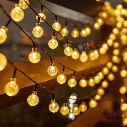 Warm golden globe string lights draped across outdoor space, creating cozy atmosphere for gatherings