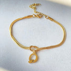Gold bracelet with a letter 'Q' charm on a light gray background