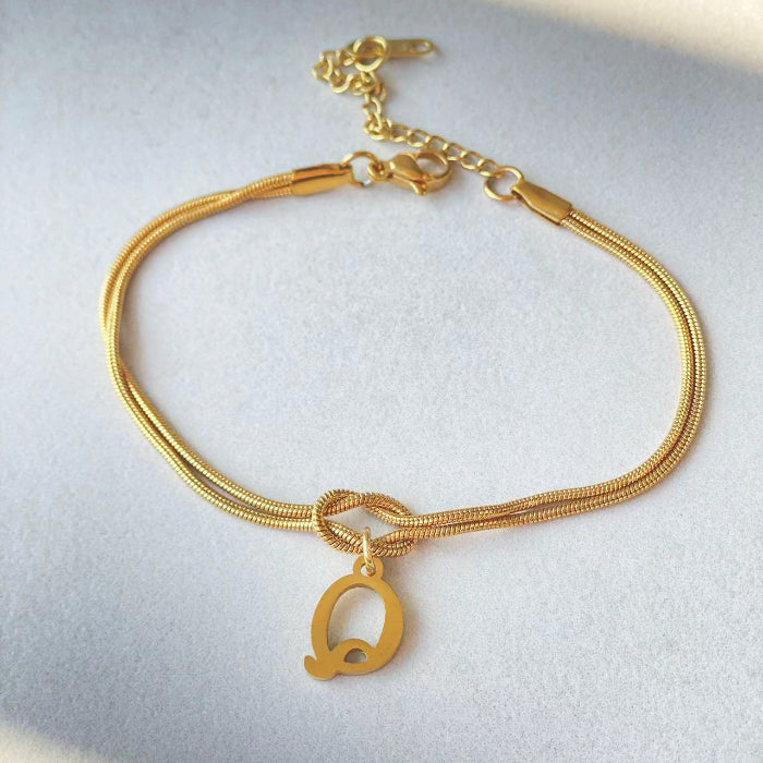 Gold bracelet with a letter 'Q' charm on a light gray background