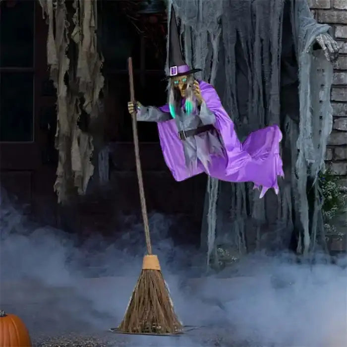 Flying witch yard decor floating in front of creepy haunted doorway with fog and decayed drapes.