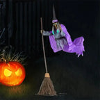 Flying witch yard decor floating beside angry-faced jack-o'-lantern on grassy yard at night.