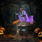 Flying witch yard decor gliding above dirt path lined with glowing pumpkins in shadowy woods.