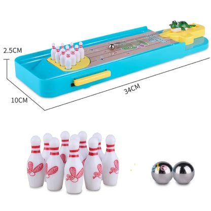 A frog-themed mini bowling game set with a blue plastic base, yellow frog launcher, white pins with red designs, and two metallic balls.