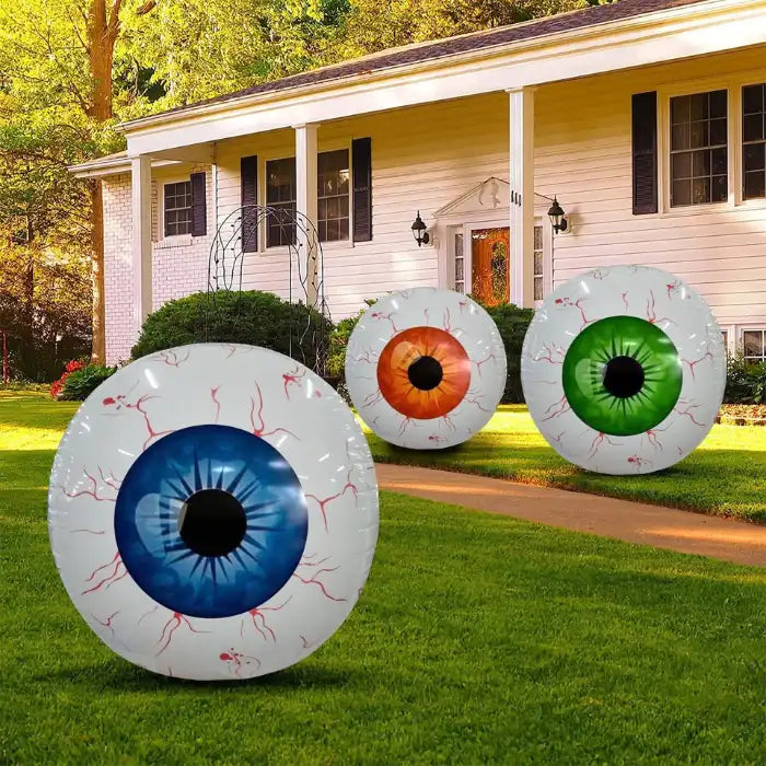 Giant inflatable eye lawn decor with blue, orange, and green eyeballs in front of white house.