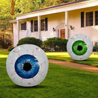 Giant inflatable eye yard display with blue and green eyeballs on grass in front of suburban house.