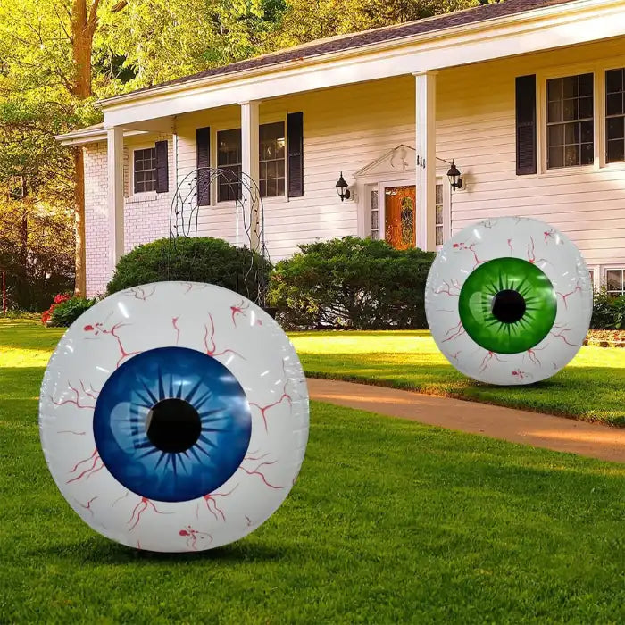 Giant inflatable eye yard display with blue and green eyeballs on grass in front of suburban house.