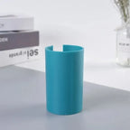 Gift wrap cutter displayed upright on table in bright blue with books and vase in background.