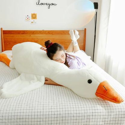 Girl comfortably hugging a large white duck plush in her room.