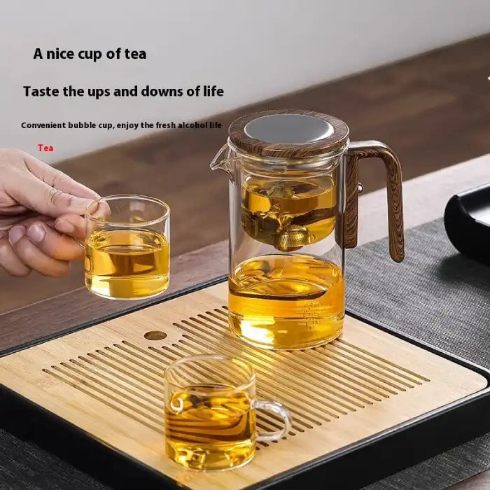 Glass Teapot with One-Click Magnetic Tea Infuser placed on bamboo tray with two filled tea cups.

