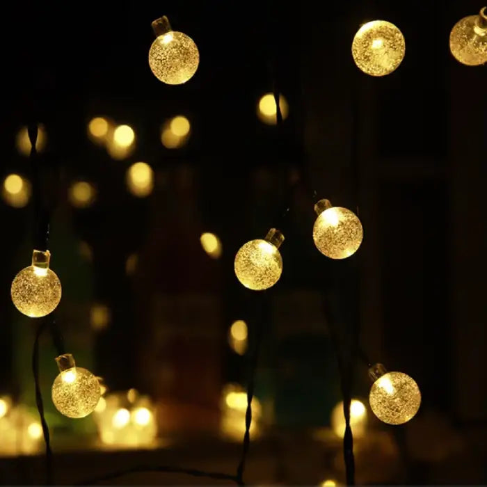 Illuminated golden orb string lights creating warm ambiance against dark background, perfect for festive decor
