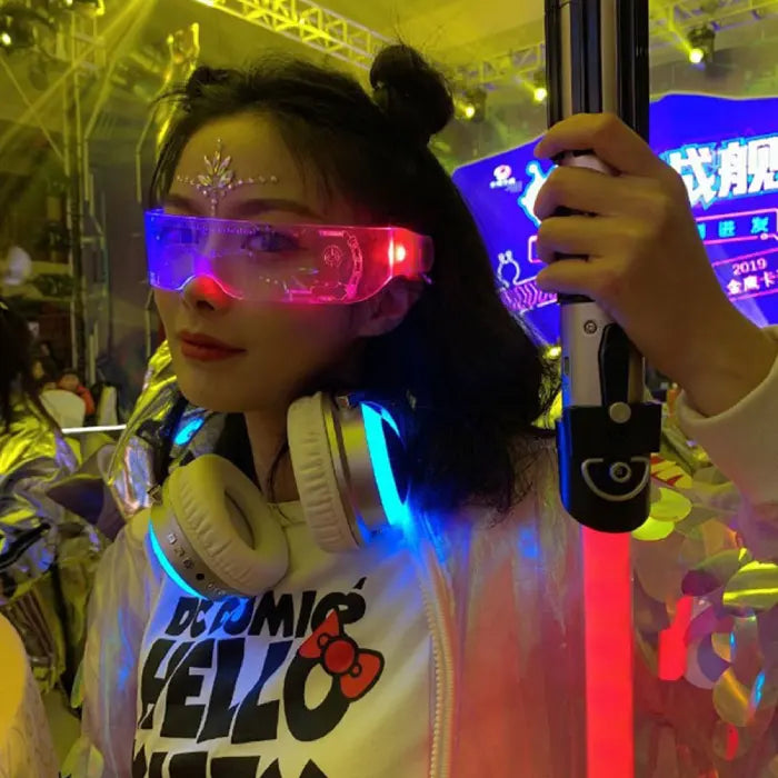 Person wearing glowing LED glasses and headphones at a vibrant party with colorful lighting.