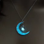 Glowing necklace with blue crescent moon and hanging heart pendant on silver chain, soft glow in dark.