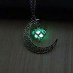 Glowing necklace with green lit heart pendant hanging from ornate crescent moon design.