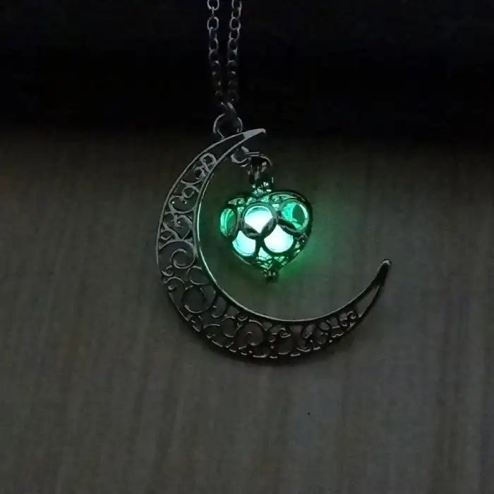 Glowing necklace with green lit heart pendant hanging from ornate crescent moon design.