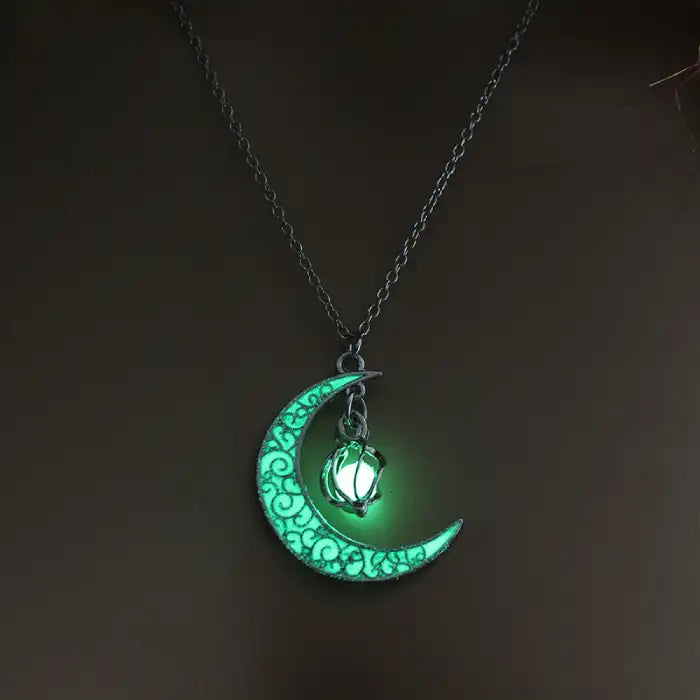 Glowing necklace featuring crescent moon and green glowing orb pendant on silver chain in darkness.