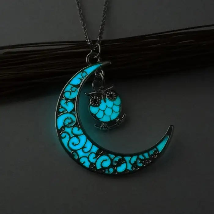 Glowing necklace with turquoise crescent moon and owl-shaped charm glowing in soft light.