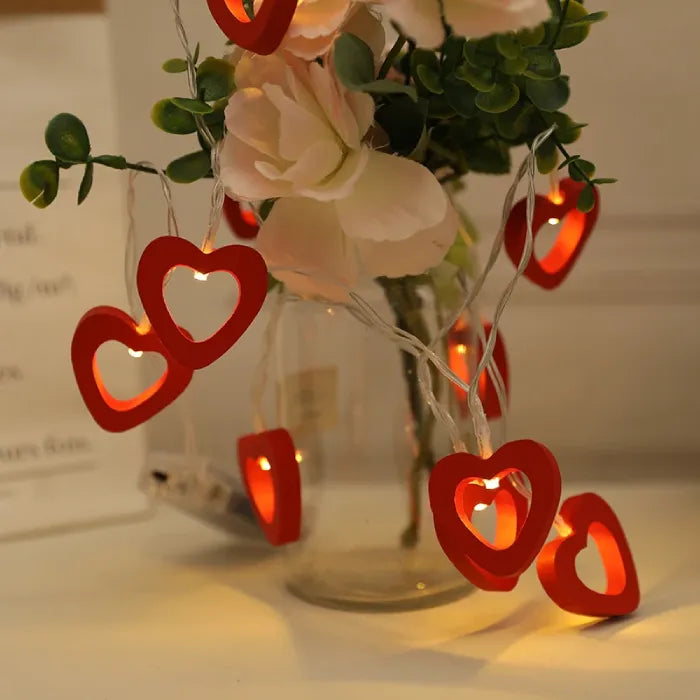 Warm glowing red heart lights in a vase with flowers, creating a romantic setting.