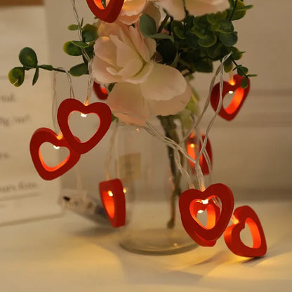 Warm glowing red heart lights in a vase with flowers, creating a romantic setting.