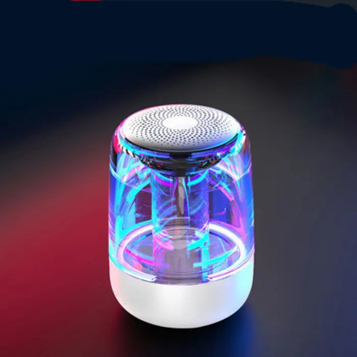 Illuminated wireless speaker with blue and pink lights, transparent body, on a dark background with red and blue hues