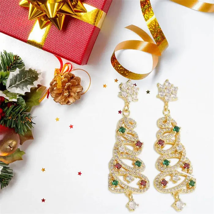 Gold Christmas tree earrings with jewel accents surrounded by festive gift decor and holiday ribbons.