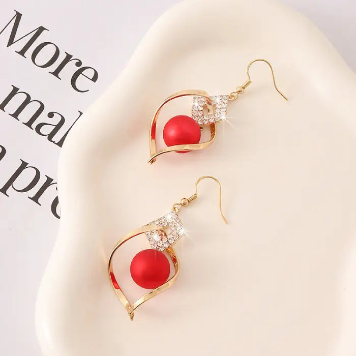 Stylish drop earrings with gold frame, red beads, and crystal embellishments for women’s jewelry.