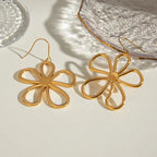 Gold flower dangle earrings with open petal design photographed in natural lighting