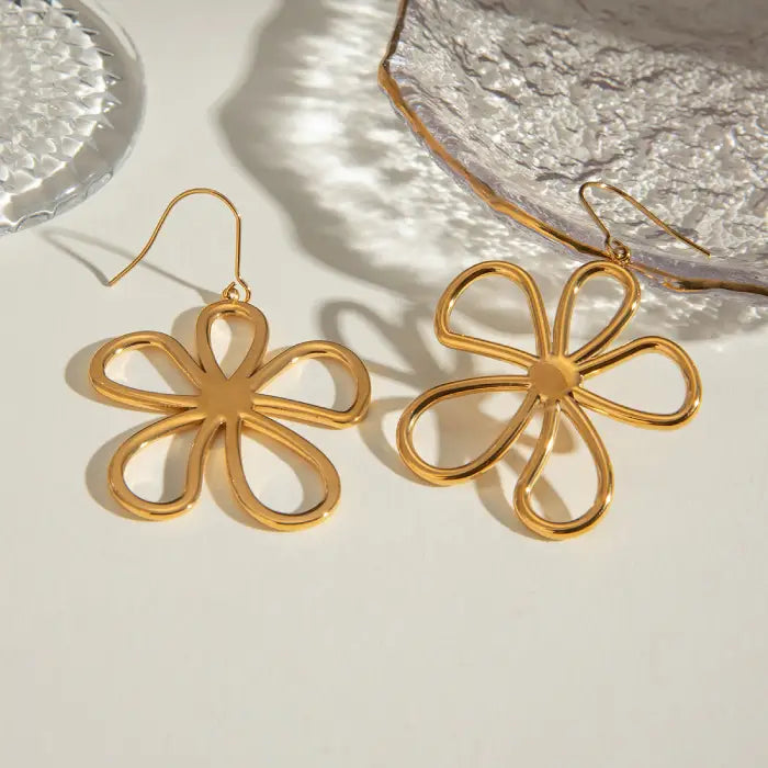 Gold flower dangle earrings with open petal design photographed in natural lighting