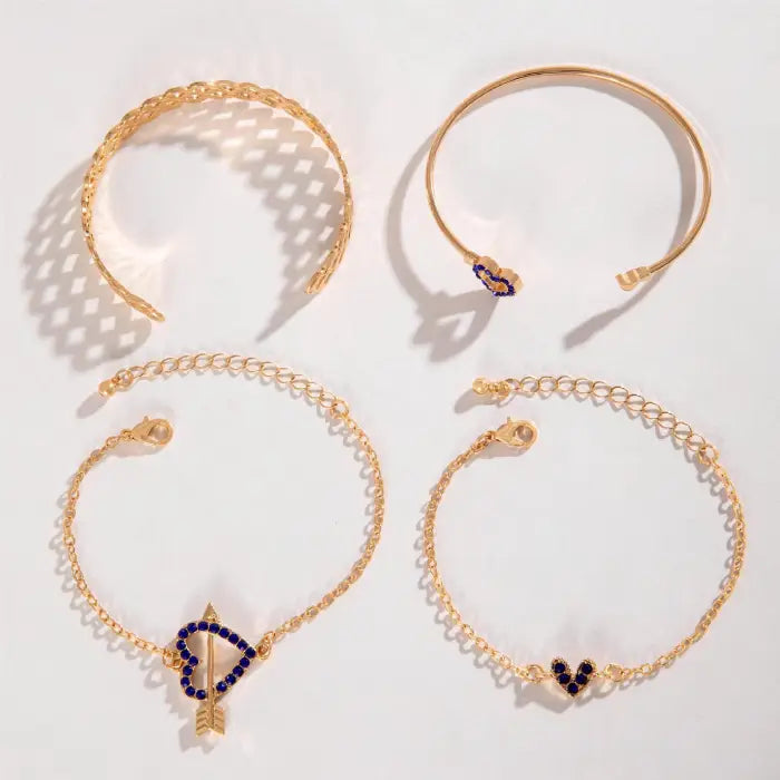 Flat display of gold bracelets with heart-shaped designs and blue gemstones in an elegant arrangement.