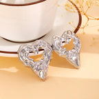 Gold heart Earrings silver metal textured heart studs displayed near teacup