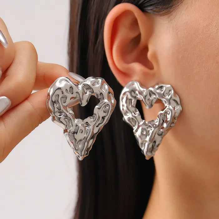 Gold heart Earrings silver textured heart studs shown worn on ear