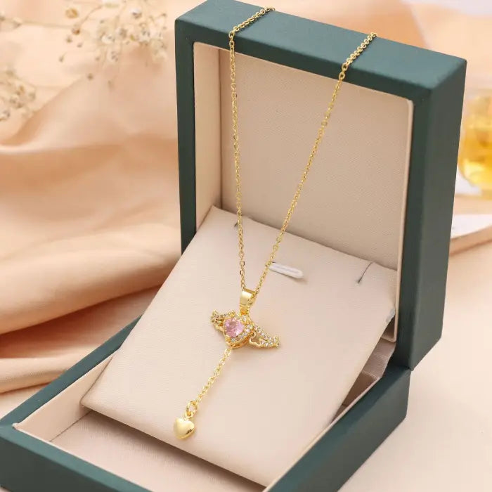 Elegant gold heart pendant necklace with pink gemstone, presented in a green jewelry box.