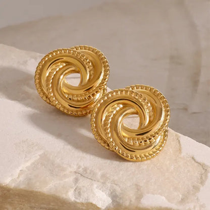 Minimalist gold knot earrings placed on a white stone surface, perfect for versatile jewelry collections.