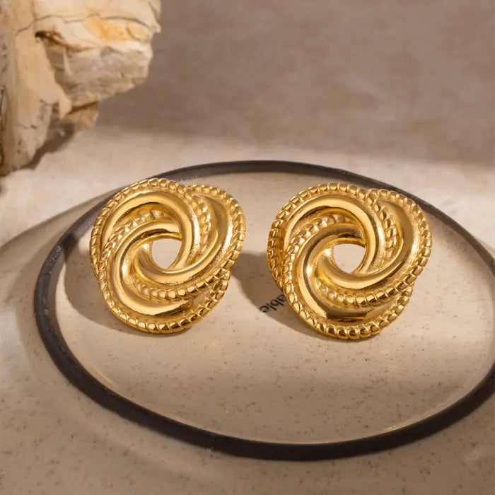 Stylish gold knot earrings displayed on a glass tray, ideal for enhancing sophisticated wardrobe choices.