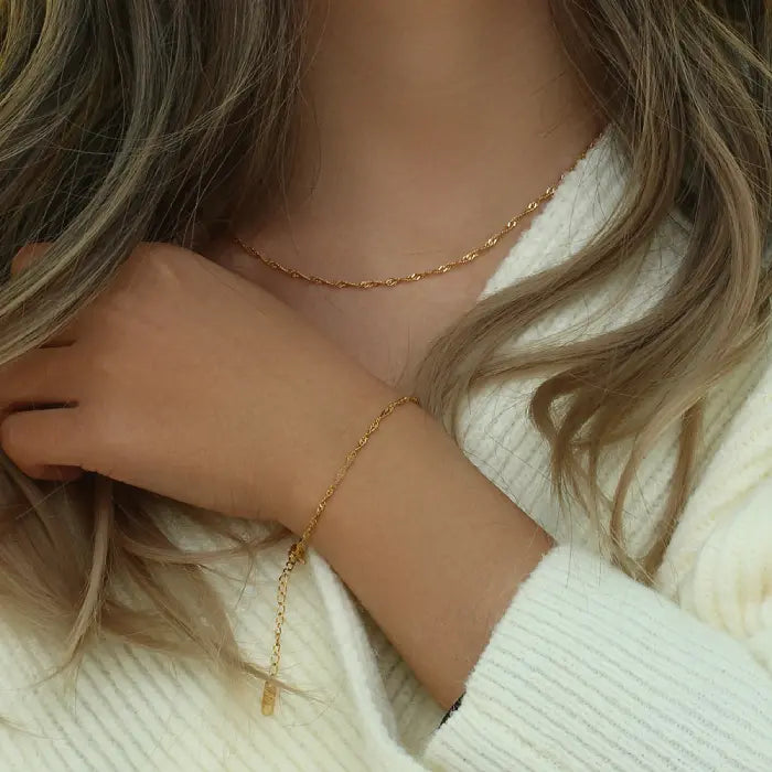 Woman wearing a gold rope chain necklace and bracelet set, stylish minimalist jewelry design.