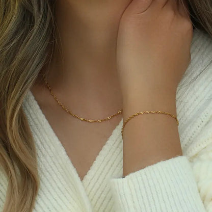 Woman showcasing a matching gold rope chain necklace and bracelet with a minimalist design.