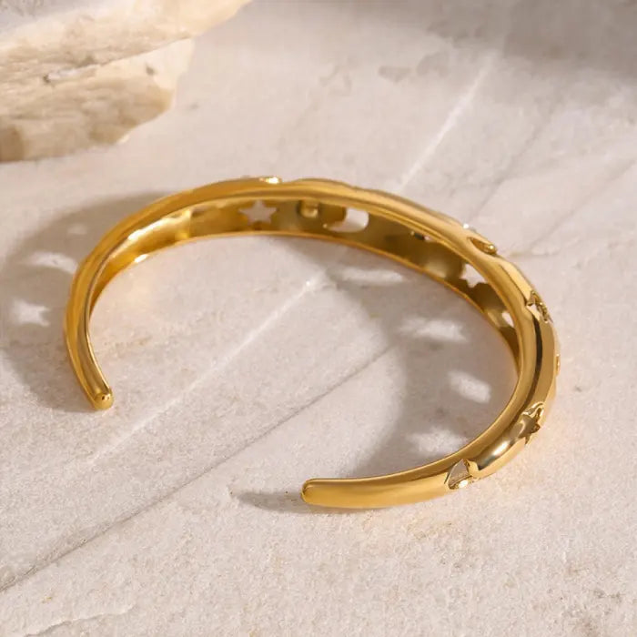 Side view of a celestial-themed gold plated bangle with moon and star motifs, detailed with sparkling stones.