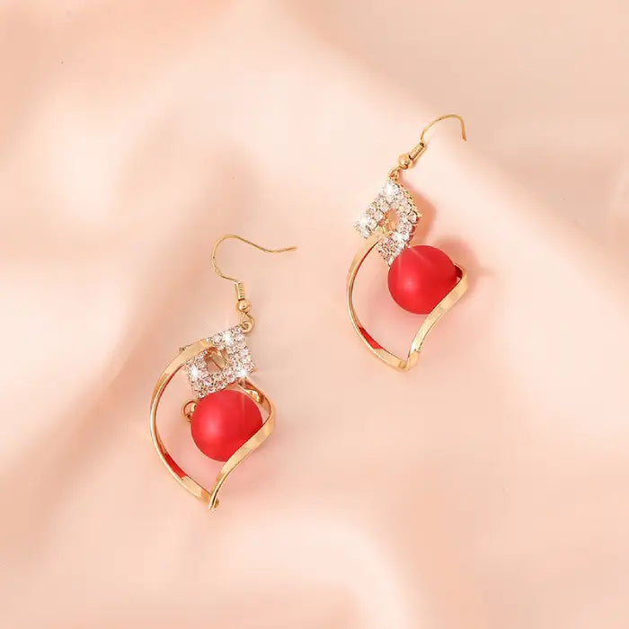 Gold drop earrings featuring red beads and crystal details, perfect for elegant evening wear.